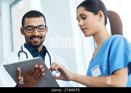 Erfolgreiche Krankenhäuser laufen auf Teamwork. Zwei junge Ärzte mit einem digitalen Tablet in einem modernen Krankenhaus. Stockfoto