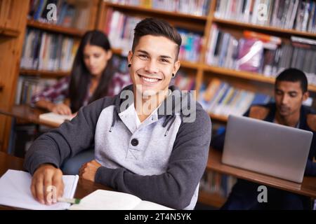 Hes ein so fleißiger Student. Beschnittenes Porträt eines hübschen jungen Studenten, der fleißig in seinem Klassenzimmer arbeitet. Stockfoto