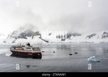 hurtigruten-Kreuzfahrtschiff und Zodiacs in eiskalten Gewässern der charlotte Bay an der danco-Küste. antarktische Halbinsel. antarktis Stockfoto