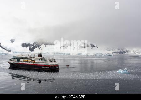 hurtigruten-Kreuzfahrtschiff und Zodiacs in eiskalten Gewässern der charlotte Bay an der danco-Küste. antarktische Halbinsel. antarktis Stockfoto