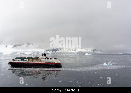 hurtigruten-Kreuzfahrtschiff und Zodiacs in eiskalten Gewässern der charlotte Bay an der danco-Küste. antarktische Halbinsel. antarktis Stockfoto