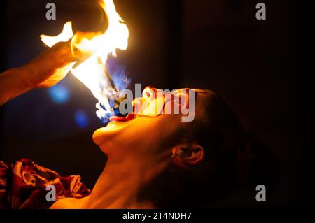 Die Frau führt am halloween-Wochenende Feuer atmet und isst, um die Leute in den Nachtclub zu locken, verkleidet als Gothic Narr. Stockfoto