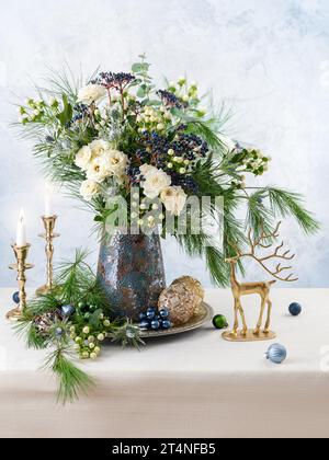 Weihnachtsdekoration, Kerzen und Blumenstrauß. Winterarrangements mit Rosen, Tannenzweigen, Winterbeeren. Weihnachtsblumen-Stillleben. Stockfoto