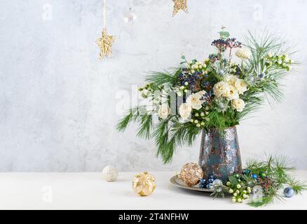 Weihnachtsdekoration, Kerzen und Blumenstrauß. Winterarrangements mit Rosen, Tannenzweigen, Winterbeeren. Weihnachtsblumen-Stillleben. Stockfoto