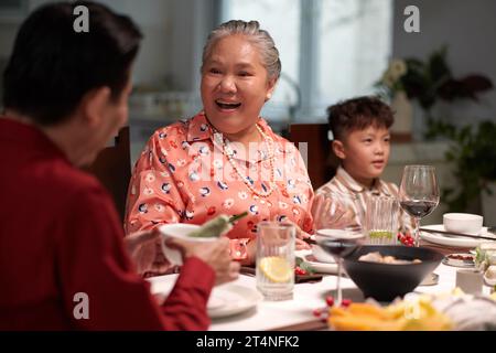 Fröhliche Seniorin, die zu ihrem erwachsenen Sohn beim Familienessen geht Stockfoto