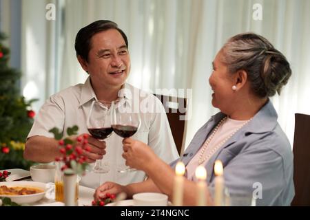 Lächelndes vietnamesisches Seniorenpaar, das zu Hause Weihnachten feiert Stockfoto