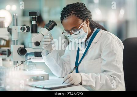 Sammeln von Informationen nach sorgfältiger Beobachtung. Ein junger Wissenschaftler, der Notizen schreibt, während er im Labor arbeitet. Stockfoto