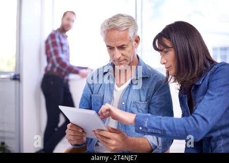 Teilen Sie ihre Ideen auf einfache Weise. Zwei Kollegen, die sich ein digitales Tablet ansehen. Stockfoto