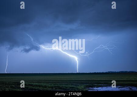 Außergewöhnlich heller Blitz trifft die Erde während eines schweren Gewitters in der Nacht Stockfoto