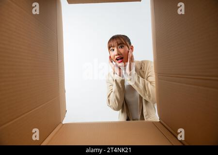 Überraschte junge asiatische Frau beim Auspacken Stockfoto