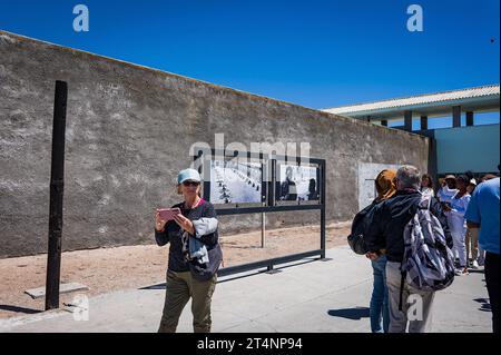 29.10.2023, xovx, Politik, Reise. Robben Island - Gefängnisinsel vor Kapstadt Besuchergruppe und Schaubild Nelson Mandelas im Gefängnishof des Zellenblocks des Hochsicherheitstrakts auf der Gefängnisinsel Robben Island vor der Küste von Kapstadt, in dem Nelson Mandela über 18 Jahre seiner Gefangenschaft in Einzelhaft inhaftiert wurde. Der spätere Präsident Südafrikas Nelson Mandela verbrachte hier von 1964 bis 1982 seiner insgesamt 27-jährigen Gefangenschaft, zumeist bei Einzelhaft und unmenschlichen Bedingungen. Robben Island ist eine Insel zwölf Kilometer vor der südafrikanischen Stadt Kapst Stockfoto