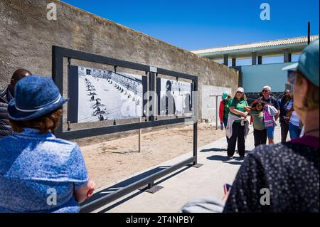 29.10.2023, xovx, Politik, Reise. Robben Island - Gefängnisinsel vor Kapstadt Besuchergruppe und Schaubild Nelson Mandelas im Gefängnishof des Zellenblocks des Hochsicherheitstrakts auf der Gefängnisinsel Robben Island vor der Küste von Kapstadt, in dem Nelson Mandela über 18 Jahre seiner Gefangenschaft in Einzelhaft inhaftiert wurde. Der spätere Präsident Südafrikas Nelson Mandela verbrachte hier von 1964 bis 1982 seiner insgesamt 27-jährigen Gefangenschaft, zumeist bei Einzelhaft und unmenschlichen Bedingungen. Robben Island ist eine Insel zwölf Kilometer vor der südafrikanischen Stadt Kapst Stockfoto