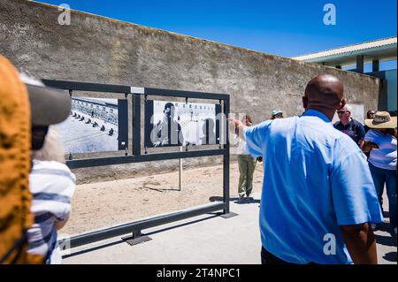 29.10.2023, xovx, Politik, Reise. Robben Island - Gefängnisinsel vor Kapstadt Besuchergruppe und Schaubild Nelson Mandelas im Gefängnishof des Zellenblocks des Hochsicherheitstrakts auf der Gefängnisinsel Robben Island vor der Küste von Kapstadt, in dem Nelson Mandela über 18 Jahre seiner Gefangenschaft in Einzelhaft inhaftiert wurde. Der spätere Präsident Südafrikas Nelson Mandela verbrachte hier von 1964 bis 1982 seiner insgesamt 27-jährigen Gefangenschaft, zumeist bei Einzelhaft und unmenschlichen Bedingungen. Robben Island ist eine Insel zwölf Kilometer vor der südafrikanischen Stadt Kapst Stockfoto