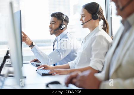 Sie werden Ihnen in wenigen Minuten helfen. Callcenter-Agenten, die Headsets tragen, während sie am Computer sitzen. Stockfoto