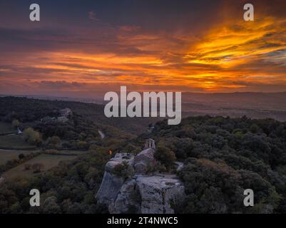 Luftaufnahme der Klippen und der Eremitage von Sant Feliuet de Savassona bei einem roten Sonnenuntergang (Osona, Barcelona, Katalonien, Spanien) Stockfoto