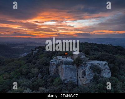 Luftaufnahme der Klippen und der Eremitage von Sant Feliuet de Savassona bei einem roten Sonnenuntergang (Osona, Barcelona, Katalonien, Spanien) Stockfoto