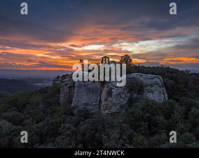 Luftaufnahme der Klippen und der Eremitage von Sant Feliuet de Savassona bei einem roten Sonnenuntergang (Osona, Barcelona, Katalonien, Spanien) Stockfoto