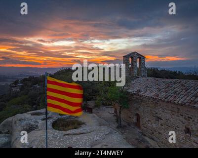 Luftaufnahme der Klippen und der Eremitage von Sant Feliuet de Savassona bei einem roten Sonnenuntergang (Osona, Barcelona, Katalonien, Spanien) Stockfoto