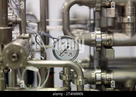 Nahaufnahme von Edelstahlrohren und Manometer. Industrieausrüstung aus Edelstahl. Selektiver Fokus. Stockfoto