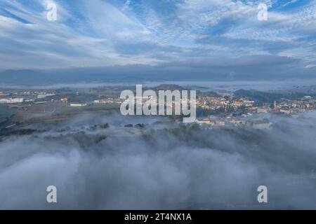 Aus der Vogelperspektive des Dorfes Roda de Ter umgeben von Nebel an einem Herbstmorgen in der Plana de Vic (Osona, Barcelona, Katalonien, Spanien) Stockfoto