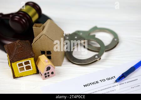 Hinweis zur Kündigung oder Räumung: Leeres Dokumentenpapier, das mit Hammer, Handschellen und kleinen Spielzeughäusern gefüllt werden kann Stockfoto