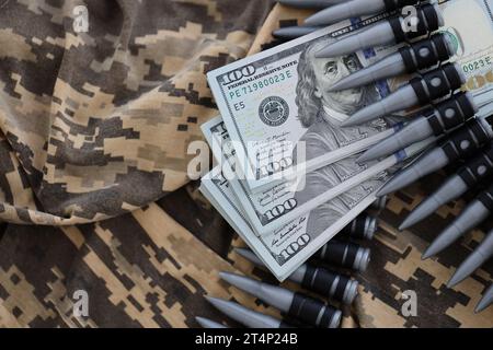 Dollarbündel und ein Maschinengewehrgürtel auf der Tarnuniform eines ukrainischen Soldaten. Konzept der Kriegsfinanzierung, Bestechung oder Spende. Hilfe für Ukrai Stockfoto