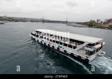 Istanbul, Türkiye. Passagierboot auf dem Goldenen Horn. Im Hintergrund die U-Bahn-Brücke Stockfoto