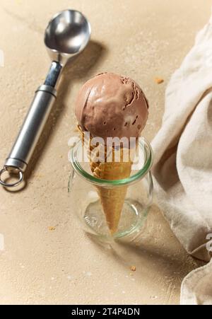 Schokoladeneis in Waffelkegel und Metallkugel auf dem Küchentisch Stockfoto