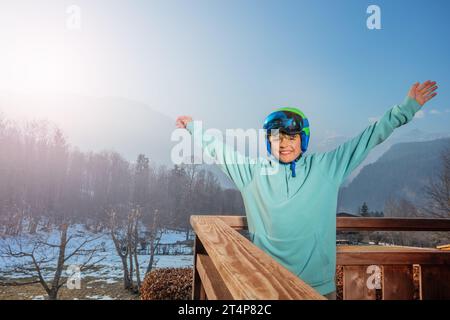 Skifahrer Boy Happy, bereit zum Skifahren auf dem Balkon über den Bergen Stockfoto