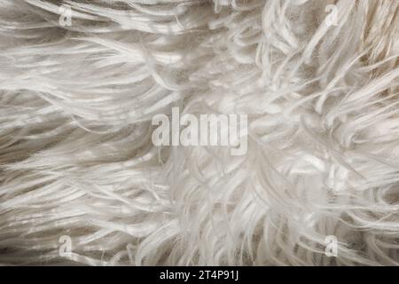 Nahaufnahme: Künstliches, flauschiges, weiß-graues Stofffell, zottiger Wollteppich mit langem Flor. Weiche Polsterung. Haarige Teppichdetails. Kunstfellstruktur, BA Stockfoto