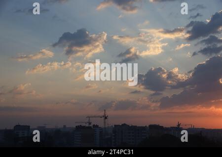 Wunderschöner Sonnenaufgang mit warmem orangenem Sonnenlicht und Sonnenstrahlen durch den bewölkten blauen Himmel Stockfoto