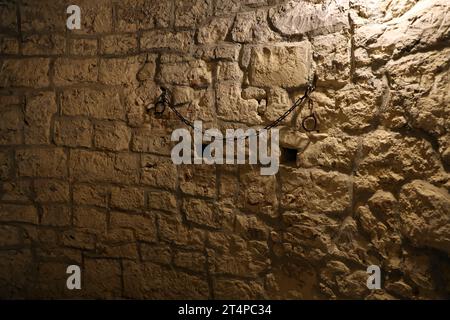 Sklaverei und Knechtschaft starke Stahlfesseln an der Steinmauer im Burgkeller oder Grabmal Stockfoto