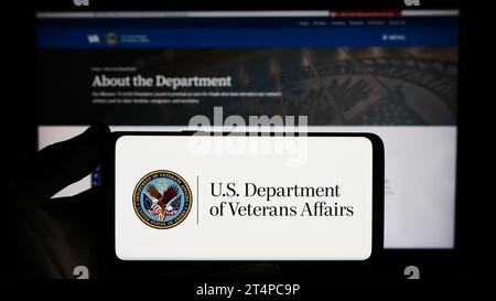 Person, die ein Smartphone mit dem Siegel des United States Department of Veterans Affairs (VA) vor der Website hält. Schwerpunkt auf dem Display des Telefons. Stockfoto