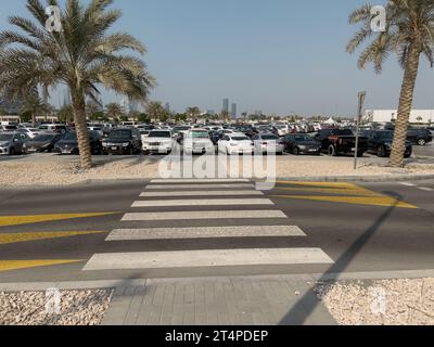 Weiß gestreifte Linien auf dem Asphalt, die den Fußgängerübergang anzeigen und zu einem Parkplatz führen. Stockfoto