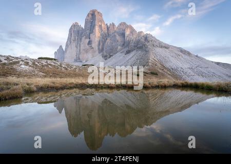 Sonnenuntergang über der massiven Felsformation der Tre Cime, die sich in einem kleinen Teich in den Dolomiten, Italien, spiegelt Stockfoto