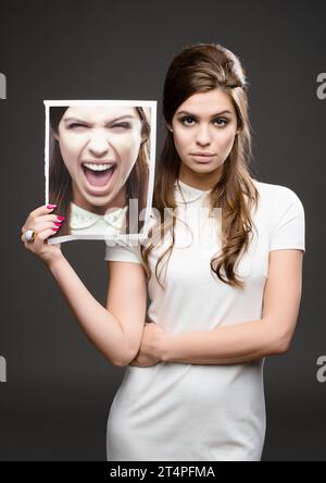 Wie ich mich innen wirklich fühle. Studio-Aufnahme einer attraktiven jungen Frau, die in 60er-Jahren gekleidet war und ein Foto von sich hält, das gegen A schreiend Stockfoto