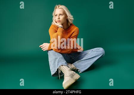 Traumhafte Frau in senfgelbem Pullover und Jeans auf türkisfarbenem Hintergrund Stockfoto