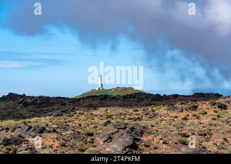 Reykjanes Lighthouse in Island, auf einem Hügel mit Blick auf den Atlantischen Ozean. Dampf aus Gunnuhver Hot Springs Stockfoto