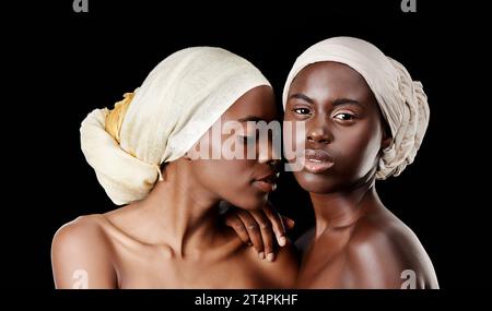 Sie ist eher eine Schwester als eine beste Freundin. Studio-Porträt von zwei schönen Frauen, die Kopftücher auf schwarzem Hintergrund tragen. Stockfoto