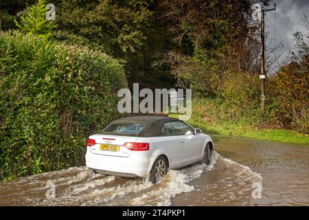 Swansea, Großbritannien. November 2023. Ein Auto fährt heute durch die überflutete Straße zum Parc Le Breos auf der Gower-Halbinsel in Swansea, als der Sturm Ciarán durch Großbritannien zieht und starke Winde und sintflutartige Regenfälle mit sich bringt. Quelle: Phil Rees/Alamy Live News Stockfoto