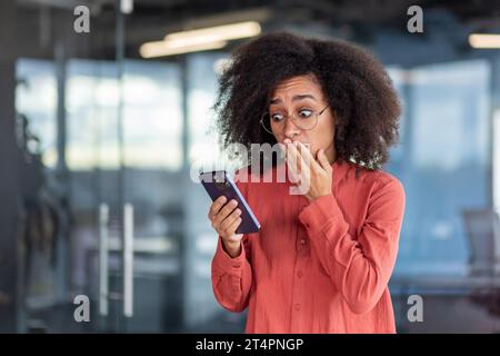 Geschäftsfrau erhielt telefonisch eine Benachrichtigung über schlechte Nachrichten, Konkurs und Geldverlust, Frau am Arbeitsplatz im Büro, die App auf dem Smartphone benutzte, enttäuscht und traurig. Stockfoto