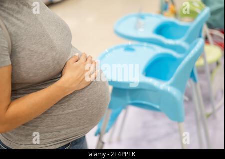 Eine kaukasische Schwangere wählt einen Hochstuhl in einem Kindergeschäft. Stockfoto