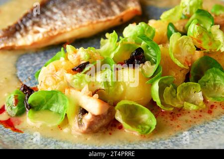 Gegrilltes Wolfsbarschfilet mit gedämpften rosenkohl, gebratenen Pilzen, Kartoffeln, karamelisierten Zwiebeln und cremiger Sauce, gesundes Abendessen. Stockfoto