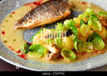 Gegrilltes Wolfsbarschfilet mit gedämpften rosenkohl, gebratenen Pilzen, Kartoffeln, karamelisierten Zwiebeln und cremiger Sauce, gesundes Abendessen. Stockfoto