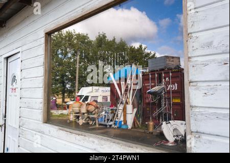 Reflexion in einem Fensterspiegel von Bric a Brac zum Verkauf. Atmosphäre, Treffen und Porträts, die mit den Begleitern der Gemeinschaft Emmaus 82, la Ville-Dieu-du-Temple (82), Emmaus, einer nationalen, europäischen und internationalen Bewegung, die 1949 von Abbe Pierre gegründet wurde, ein Mittagessen mit dem ganzen Team teilte und Kleidung, Gebrauchtkleidung, Spielzeug, Gebrauchtmöbel und andere nützliche Gegenstände, Fahrräder, Radios, fernseher verkaufte, Computer, Müll und Recycling. Eines der Grundprinzipien von Emmaus ist Selbstständigkeit durch Arbeit. Frankreich, Ville-Dieu-du-Temple am 31. Oktober 2023. Foto: Patricia Huchot-Boissier Stockfoto