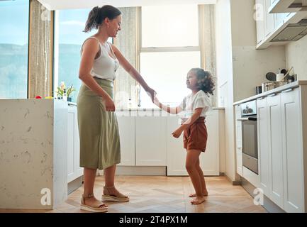 Mutter und kleine Tochter tanzen zusammen und haben aktiven Spaß in der Küche zu Hause. Kind und Kindermädchen, die Spaß beim Tanzen und Spielen haben Stockfoto