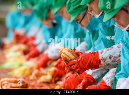 Seoul, Südkorea. November 2023. Während der diesjährigen Kimchi-Sharing-Veranstaltung im Hauptquartier der Hana Bank in Seoul wird Kohl von einem Freiwilligen gewürzt. Etwa 200 Menschen beteiligen sich an der Herstellung von Kimchi und liefern sie an die Unterprivilegierten. Scharfe fermentierte Kimchi sind ein Grundnahrungsmittel koreanischer Küche. Häufig verwendetes Gemüse sind Chinakohl und Rettich. (Foto: Kim Jae-Hwan/SOPA Images/SIPA USA) Credit: SIPA USA/Alamy Live News Stockfoto