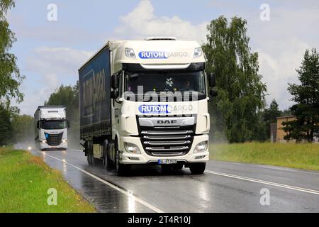 DAF XF Rutom Cargo und Iveco S-Way Sattelauflieger transportieren an einem regnerischen, donnernden Tag Güter auf der Autobahn. Salo, Finnland. Juli 2023. Stockfoto