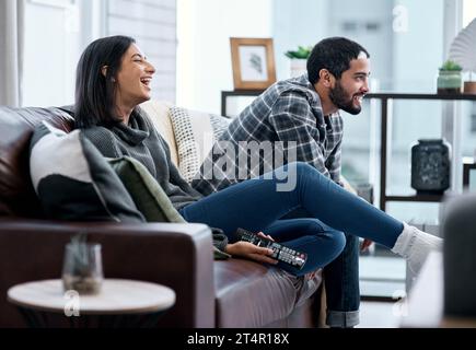 Samstags sehen wir Sport. Ein junges Paar, das zu Hause fernsieht. Stockfoto