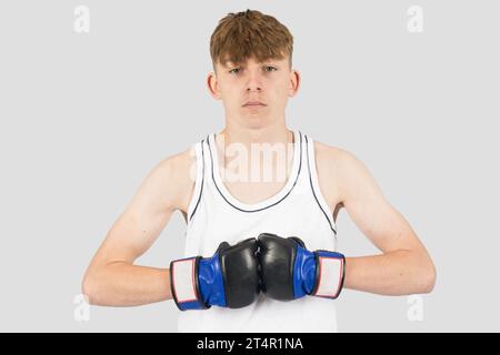 Ein kaukasischer Teenager mit MMA-Boxhandschuhen posiert Stockfoto